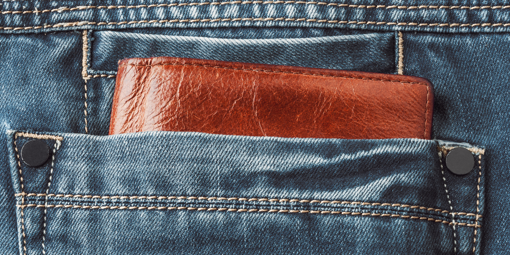 braune Lederbörse, steckt in Gesäßtasche aus Jeansstoff