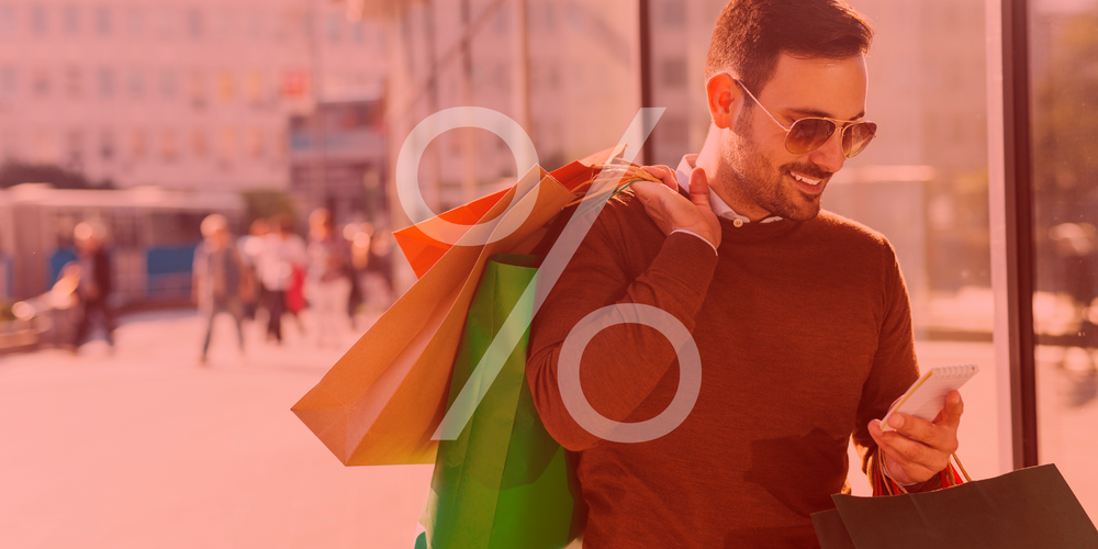 Sale Herren, Mann mit Einkaufstüten, Sonnenbrille, Smartphone in der Hand, Prozentzeichen über dem Bild, Stadtszene im Hintergrund