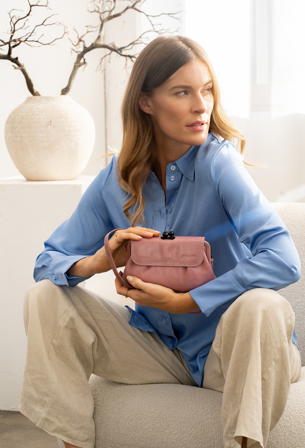 aunts&uncles, Rucksack, Frau mit Rucksack im Stadthof, lässiger Look, urbanes Umfeld, Vintage-Stil, olivgrün mit Lederdetails, nachhaltiges Design, Streetstyle, Outdoor-Atmosphäre