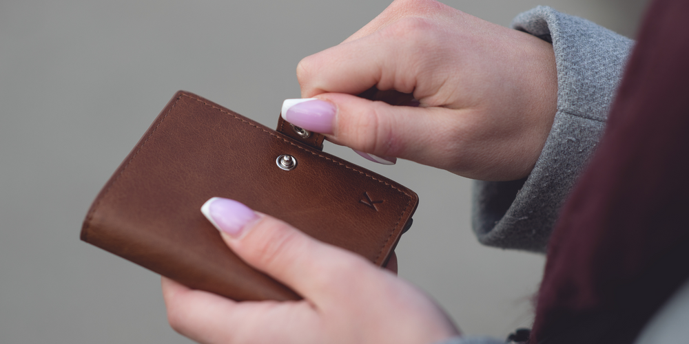 braune Leder-Geldbörse, Nahaufnahme, wird mit Fingern geöffnet